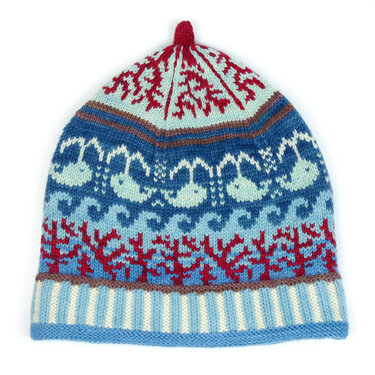 Knitted hat with blue whale and wave motifs, red coral patterns, and a striped brim.