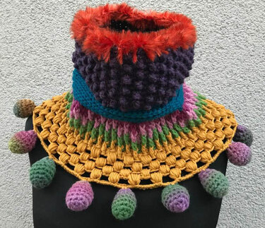 Kräftig bunter Häkel-Halskragen mit rotem flauschigem Rand, violetter Noppenstruktur, türkisfarbener Bandkante und gelbem offenen Saum mit farbigen Bommeln.