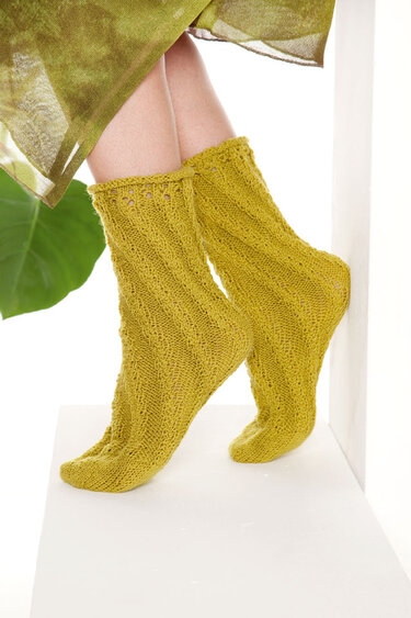 Gestrickte senfgelbe Socken mit Rippen- und Zopfmuster an Beinen