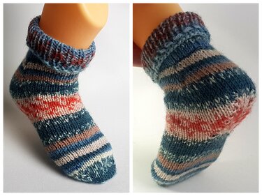 Gestreifte handgestrickte Kindersocken an einem Fußmodell in Blau, Orange und Naturtönen