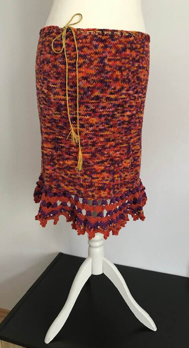 Mannequin trägt gehäkelten Tube-Rock in Orange-Rot-Violett mit Kordelzug und gehäkelter Spitze am Saum