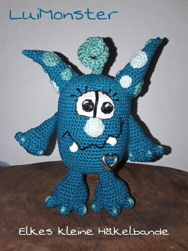 Gehäkeltes blaues Monster-Amigurumi mit Hörnern und Herzanhänger