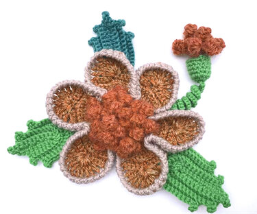 Gehäkelte Blume mit orange-beigen Blütenblättern, grünen Blättern und Knospe auf weißem Hintergrund