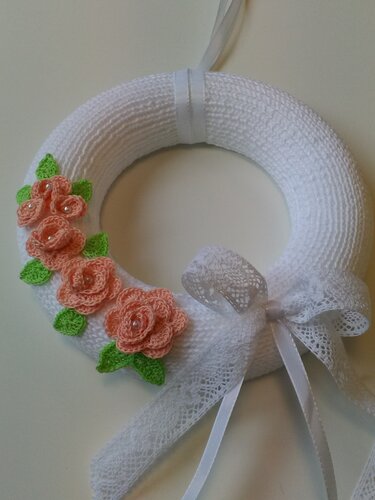 Weißer Garnkranz mit apricotfarbenen gehäkelten Rosen, grünen Blättern und weißer Spitzen- und Satin-Schleife
