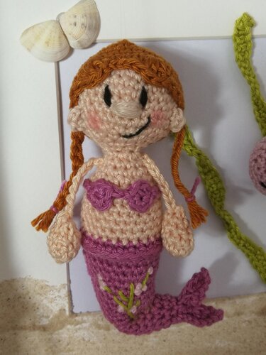 Gehäkelte Amigurumi-Meerjungfrau mit geflochtenen Zöpfen und lilafarbener Flosse