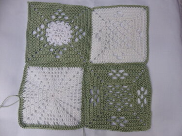 Vier verbundene Granny-Squares mit sichtbarer Naht und unterschiedlichen Häkelmustern