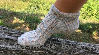 Detailaufnahme einer gestrickten Kurzsocke mit Zopf-, Ajourstreifen und Rippbündchen