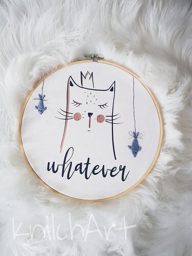 Rundes Motiv in Holzrahmen: minimalistische Katze mit Krone, zwei hängenden Fischen und dem Schriftzug „whatever“ auf weißem, flauschigem Untergrund.