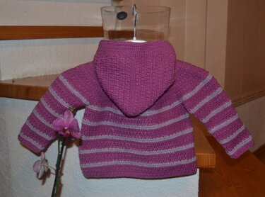 Rückansicht einer gehäkelten Baby-Kapuzenjacke in Violett mit hellgrauen Streifen