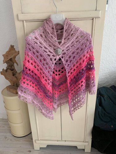Gehäkeltes Dreieckstuch mit Lochmuster und Farbverauf in Rosa und Lila, gehalten von einem Zierknopf