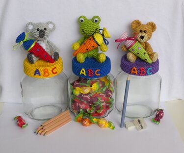 Drei Glasgefäße mit gehäkelten Tierfiguren (Koala, Frosch, Bär) und kleinen Schultüten, ABC-Buchstaben auf den Deckeln