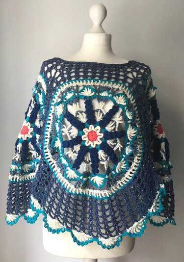 Gehäkelter Damenponcho in Blau- und Cremetönen mit großem Mandala-Motiv auf Schaufensterpuppe