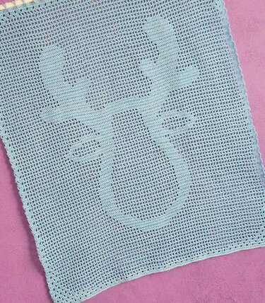 Gehäkeltes Filetquadrat mit stilisiertem Schneemann-Motiv auf lila Untergrund