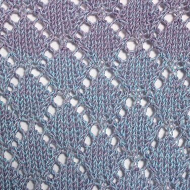 Close-up of diamond lace knitting in variegated blue and lilac yarn