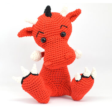Roter gehäkelter Amigurumi-Drache mit weißen Hörnern und Krallen