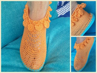 Handgehäkelter orangefarbener Slipper mit Lochmuster, Rosetten am Knöchel und türkisfarbener Sohle auf blaugrünem Sitzkissen.
