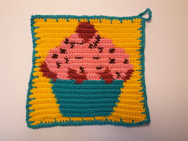Quadratischer Topflappen mit pixelartigem Cupcake‑Motiv auf gelbem Grund