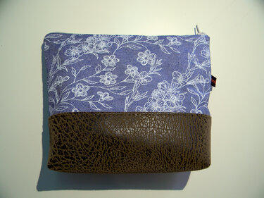 Rechteckige Kosmetiktasche aus blauem Stoff mit weißem Blumenmuster und dunkelbraunem Kunstlederboden