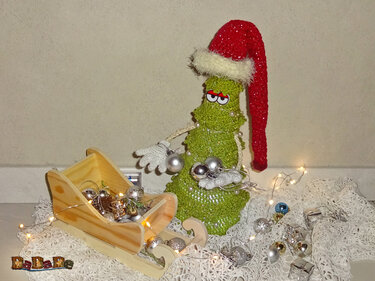 Skurriler gehäkelter Tannenbaum mit roter Zipfelmütze, Holzschlitten und Lichterkette
