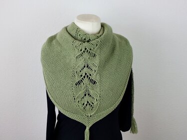 Hellgrünes gestricktes Dreieckstuch mit Blatt‑Lochmuster und Quaste auf einer Schneiderpuppe