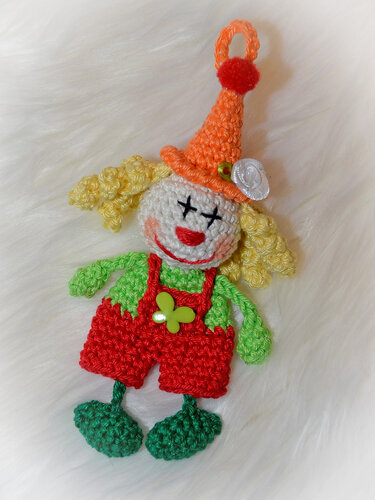 Hand-crocheted clown keychain with orange hat, curly yellow hair and red overalls