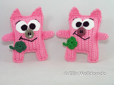 Zwei rosa Amigurumi-Figuren als DIY-Inspiration, mit Knopf-Nasen und gehäkeltem Kleeblatt