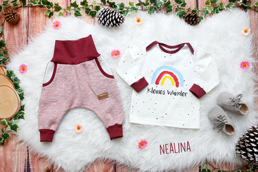 Baby-Set: Regenbogen-Langarmshirt und rosa-beerenfarbene Hose auf flauschigem Teppich