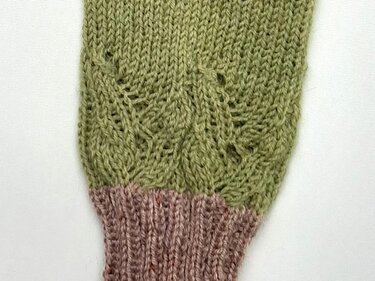 Gestrickte grün-rosa Armstulpe mit Blattmuster und rosa Rippbündchen
