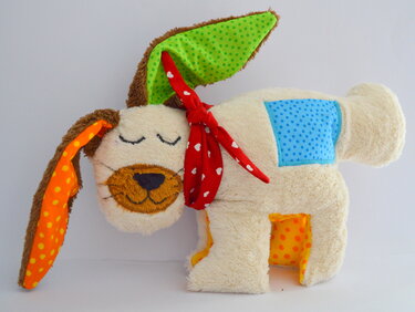 Beigefarbenes Kuscheltier als Nähidee mit gepunkteten Innenohren, blauem Seitenpatch und rotem Halstuch