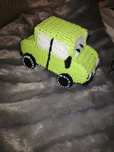 Nahaufnahme eines grünen Amigurumi-Autos mit sichtbarer Karosserie und Rädern