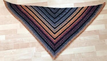Flat-laid striped triangle crochet shawl showing alternating color-change rows and textured bands