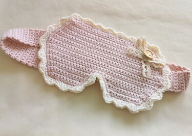 Gehäkelte Schlafmaske rosa mit weißer Rüsche, Schleife und Holzknopf