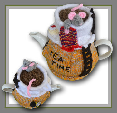 Two knitted tea cozies on white ceramic teapots — orange 'TEA TIME' cozy with a mouse in a striped scarf; smaller cozy with a mouse, pink tail and bee detail.