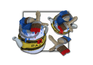 White and yellow knitted teapot cozy with paint-splatter motif and knitted brush-shaped accessories