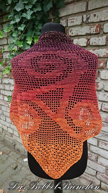 Gehäkeltes Dreieckstuch Violett–Orange auf schwarzer Schaufensterpuppe vor Ziegelwand