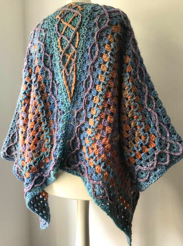 Mehrfarbiger gehäkelter Poncho‑Überwurf mit Granny‑Clustern und zopfartigen Relieflinien auf Büste