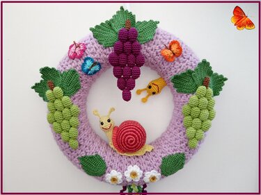 Gehäkelter runder Türkranz in Flieder mit grünen und violetten Trauben, Blättern, Schmetterlingen, einer Schnecke und einer Raupe