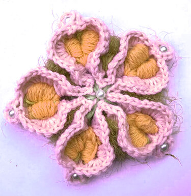 Gehäkelte Blüte mit sechs rosa Blütenblättern, orangefarbenen Innenkernen und Perlen