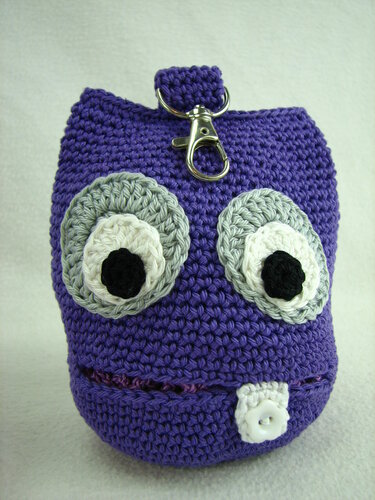 Lila gehäkelte Monstertasche mit zwei großen Augen, weißem Knopfzahn und silbernem Karabiner.