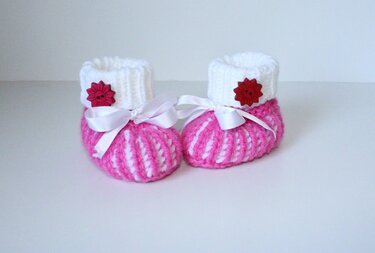 Gestrickte Babyschuhe rosa und weiß mit Schleifendetail und dekorativem Knopf