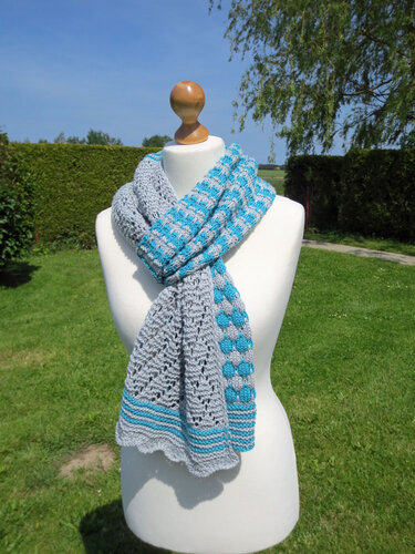 Gestrickter Schal in Grau und Türkis mit Loch- und Karomuster an Schaufensterpuppe