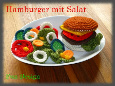 Handgehäkelter Burger mit bunten Häkel-Salatstücken auf weißem Teller