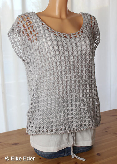 Light grey openwork crochet top on a mannequin, wide neckline, short sleeves and drawstring hem over a white undershirt.