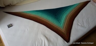 Crochet triangle shawl with brown-to-teal gradient and textured stitches laid flat.
