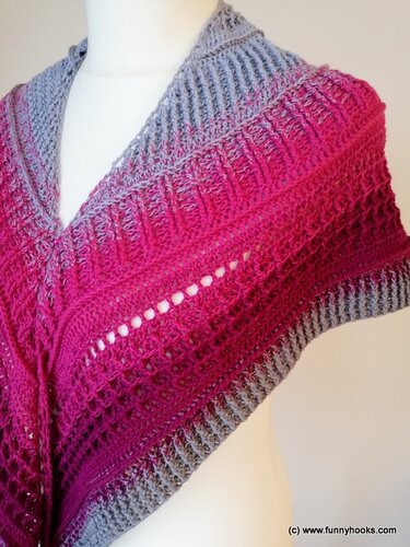 Mannequin wearing triangle crochet shawl in gray to pink ombré with lace openwork, textured stitch bands, and ribbed edging