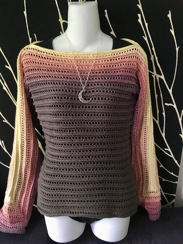 Gehäkelter Damenpullover mit grauem Körper und rosa-gelben Verlaufärmeln auf Schaufensterpuppe