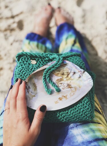 Detailaufnahme: grünes gehäkeltes Täschchen mit Kordelzug und kleinem Zierplättchen