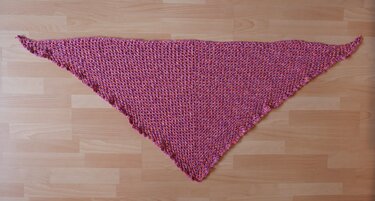 rosa gehäkeltes Dreieckstuch auf hellem Holzboden