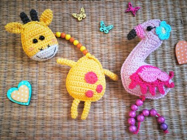 Gehäkelte gelbe Giraffe und pinker Flamingo mit Perlen auf geflochtenem Untergrund