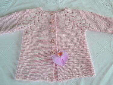Rosa Babyjacke, kraus rechts gestrickt, mit Blattranken an Schultern und Knopfleiste